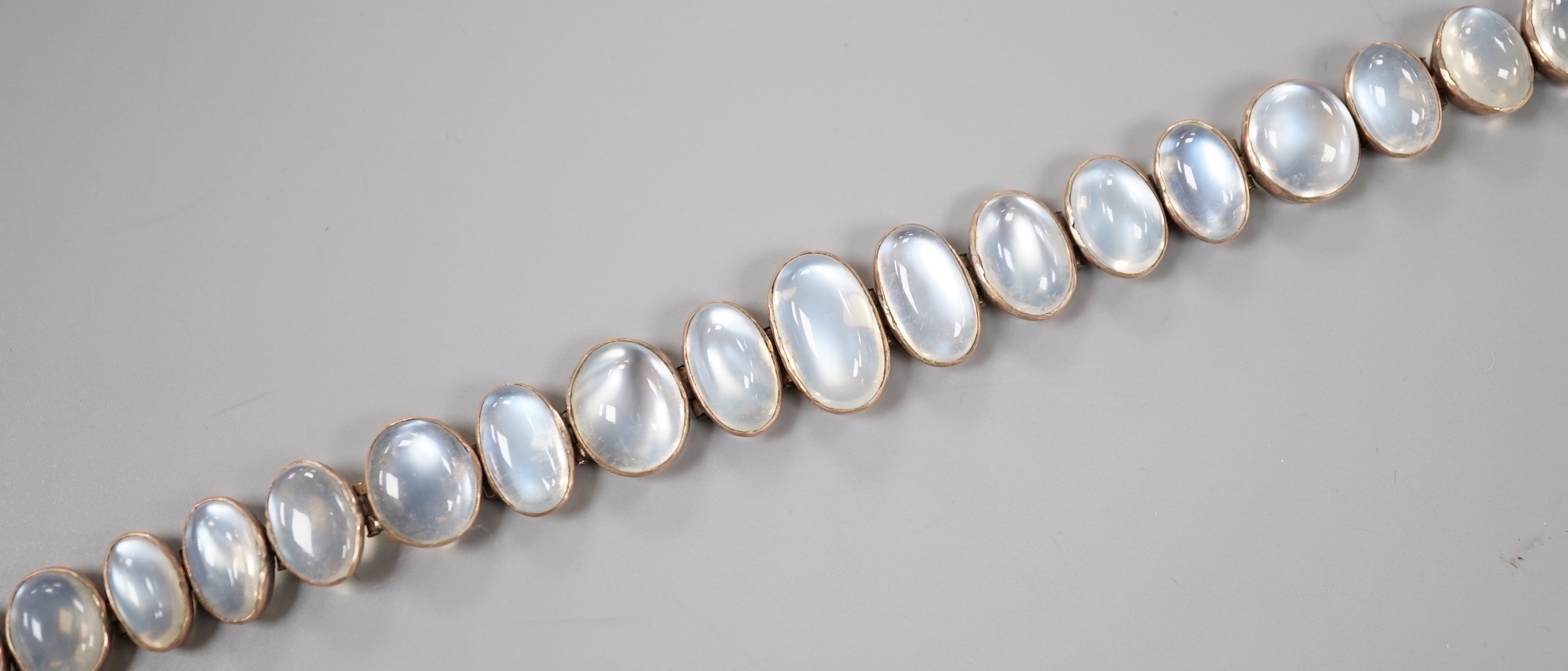 An Edwardian white and yellow metal, graduating oval cabochon moonstone set bracelet, 18cm, gross weight 14.6 grams.